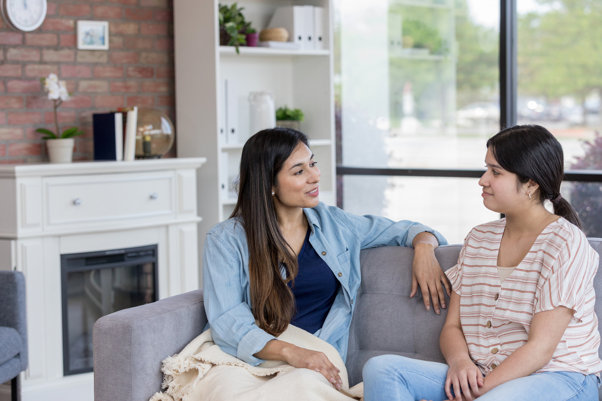 Mid adult mom and teen girl talk in living room